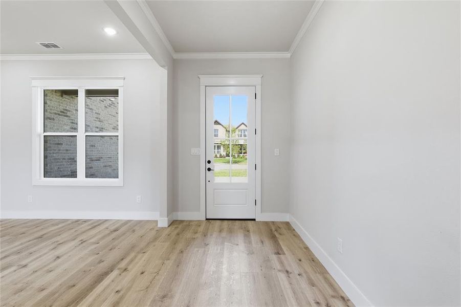 Light wood-finish flooring extending throughout, complemented by crisp white baseboards and crown molding