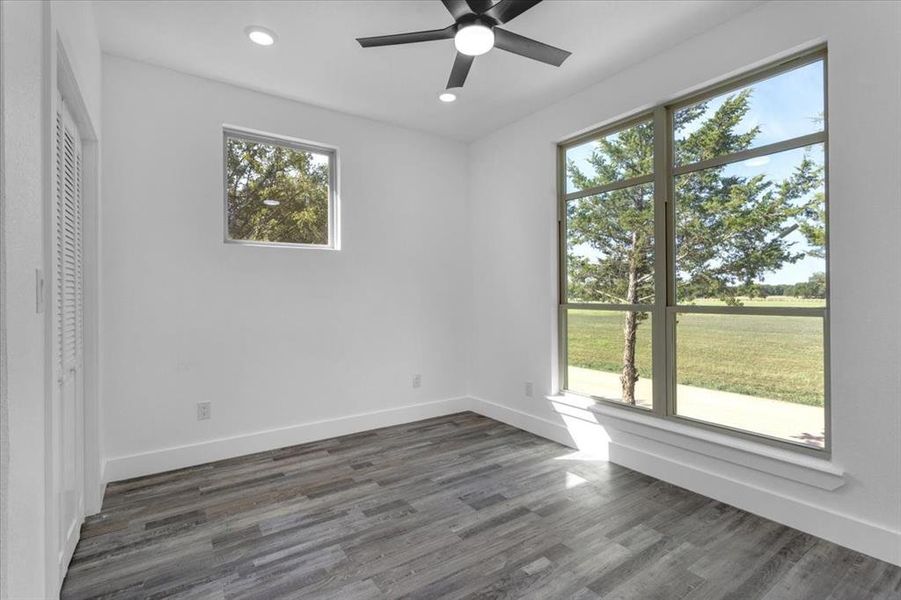 Unfurnished bedroom featuring dark hardwood / wood-style flooring, multiple windows, and ceiling fan