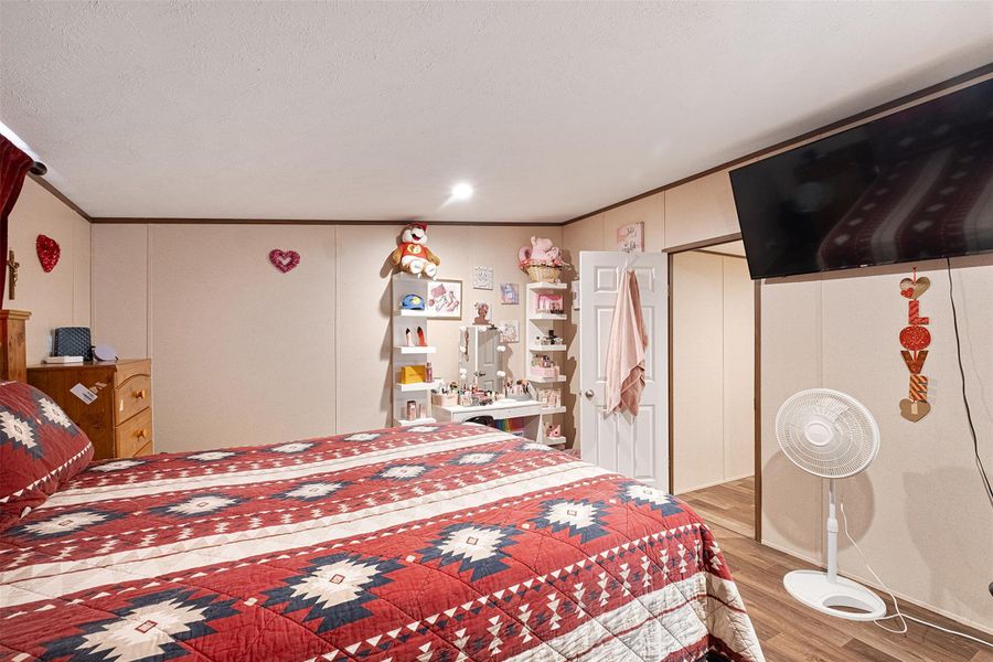 Bedroom featuring crown molding, light wood-style floors, a decorative wall, and recessed lighting