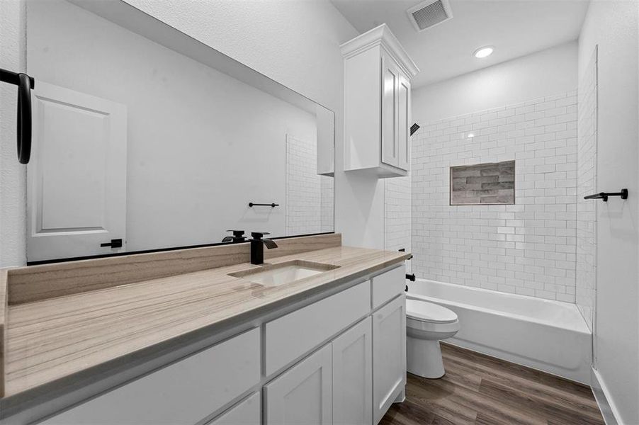 Full bathroom with vanity, toilet, wood-type flooring, and tiled shower / bath