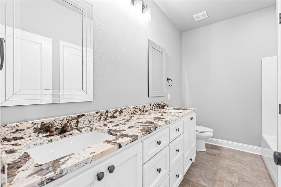 Hall bathroom featuring a sink, toilet, double vanity, and bathtub. Hall bathroom featuring a sink, toilet, double vanity, and bathtub.