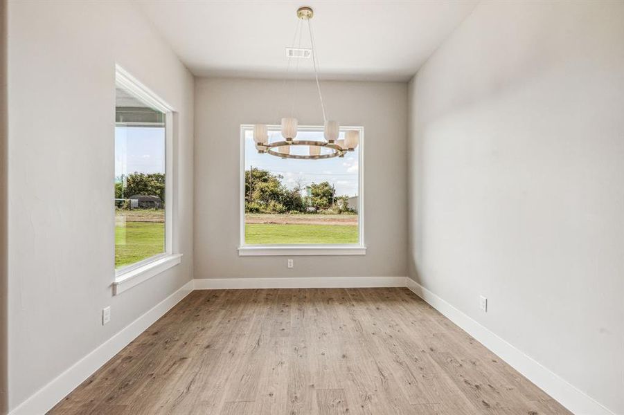 Unfurnished dining area featuring light hardwood / wood-style floors and a notable chandelier