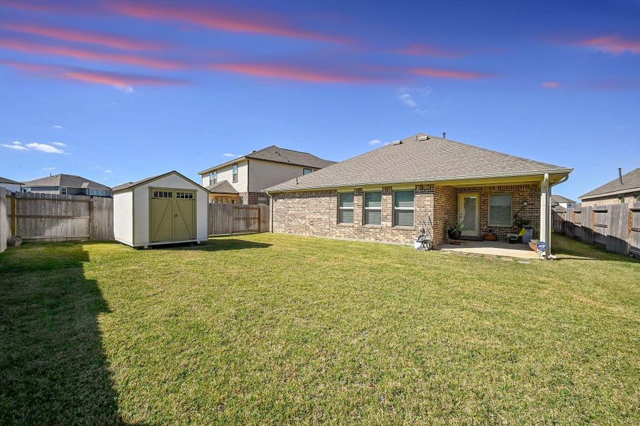 The light-colored storage shed with a gable roof and double doors adds both charm and utility The light-colored storage shed with a gable roof and double doors adds both charm and utility