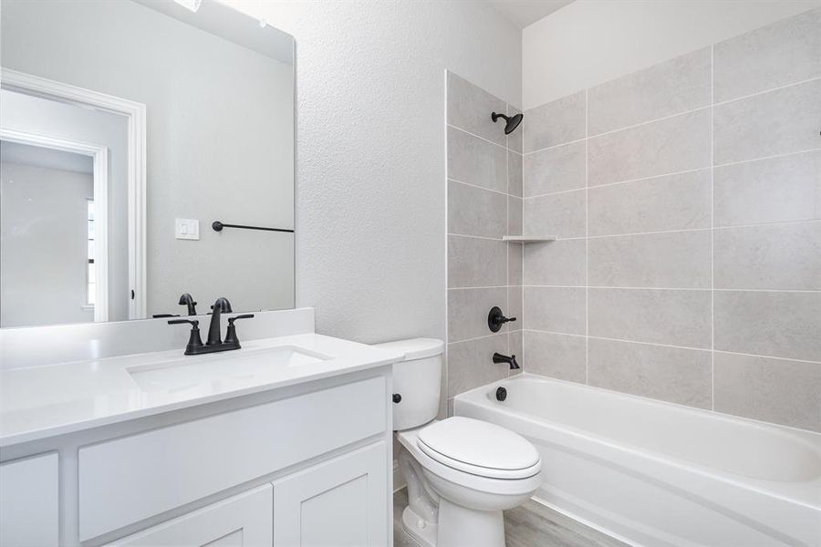 Full bathroom with vanity, tiled shower / bath combo, wood-type flooring, and toilet