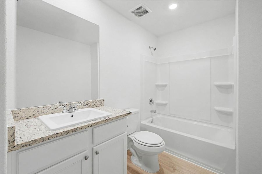Full bathroom featuring vanity, bathtub / shower combination, light wood-style floors, and recessed lighting