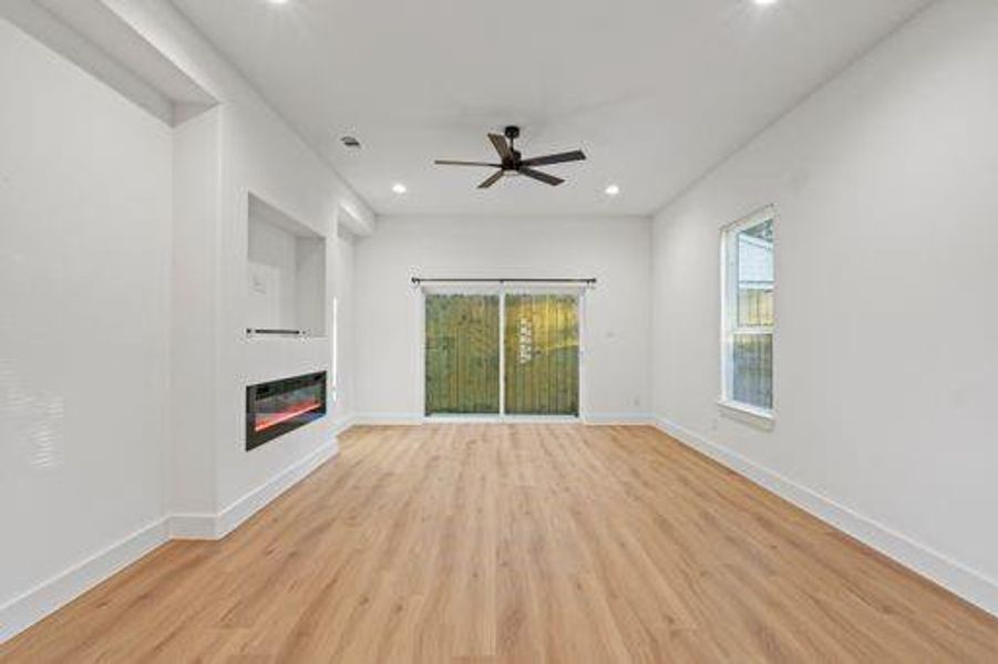 Unfurnished living room with light wood-type flooring and ceiling fan