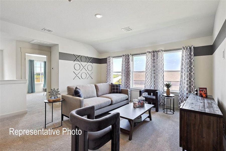 Spacious carpeted room featuring multiple windows, recessed lighting, and a partial vaulted ceiling