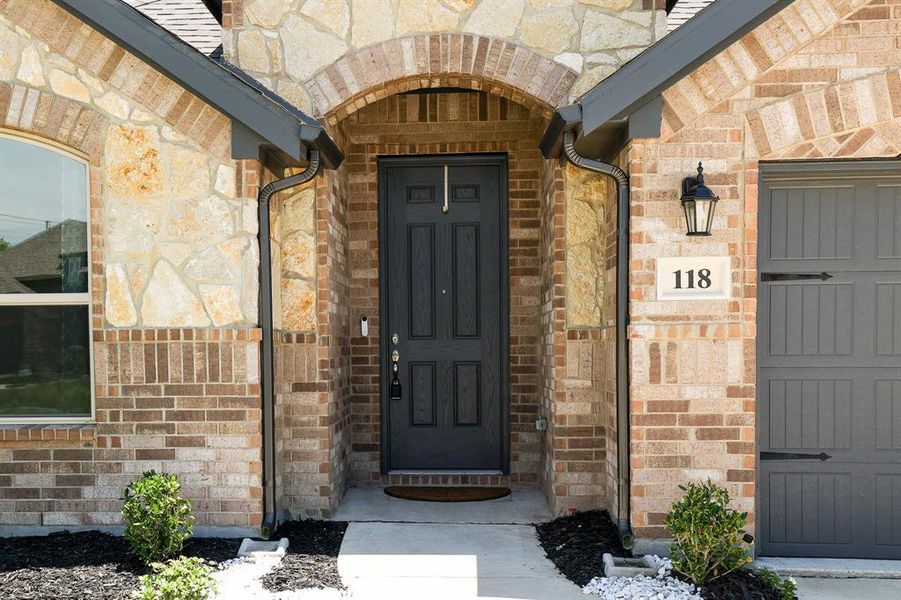 View of exterior entry featuring brick siding and stone siding