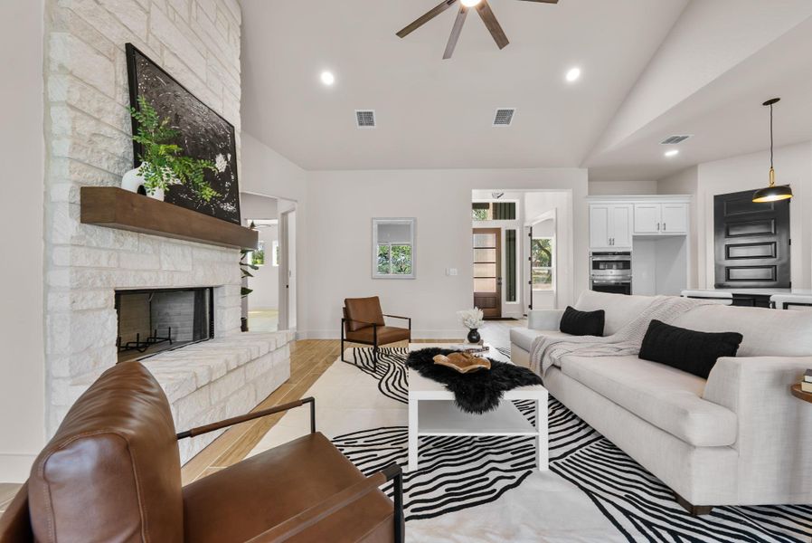 A striking fireplace crafted from light-colored stone commands attention in this spacious living area.