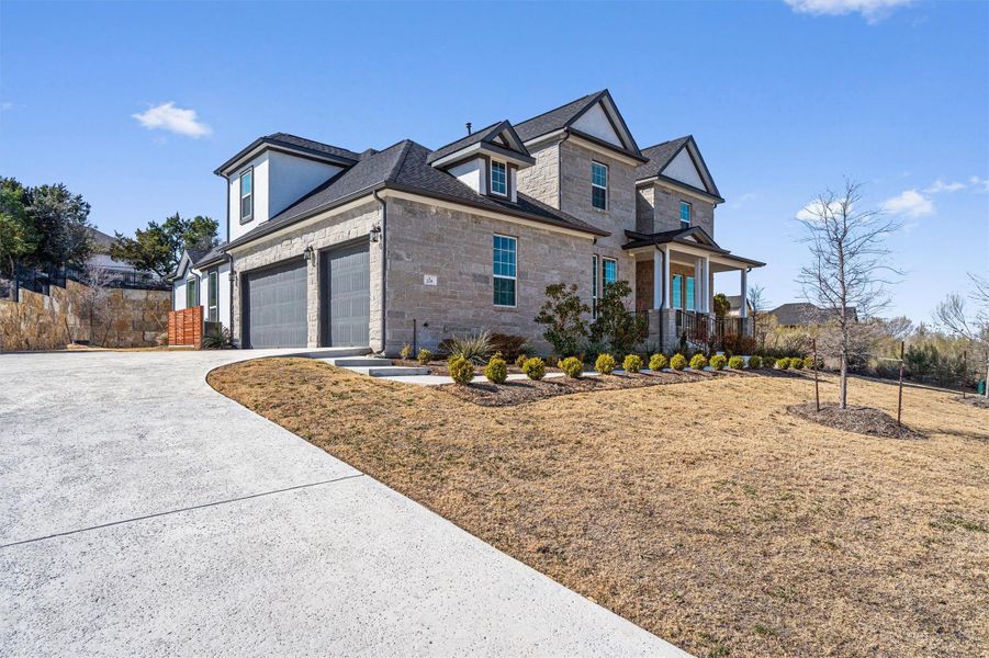 View of front of home with stone siding, driveway, and a front yard View of front of home with stone siding, driveway, and a front yard