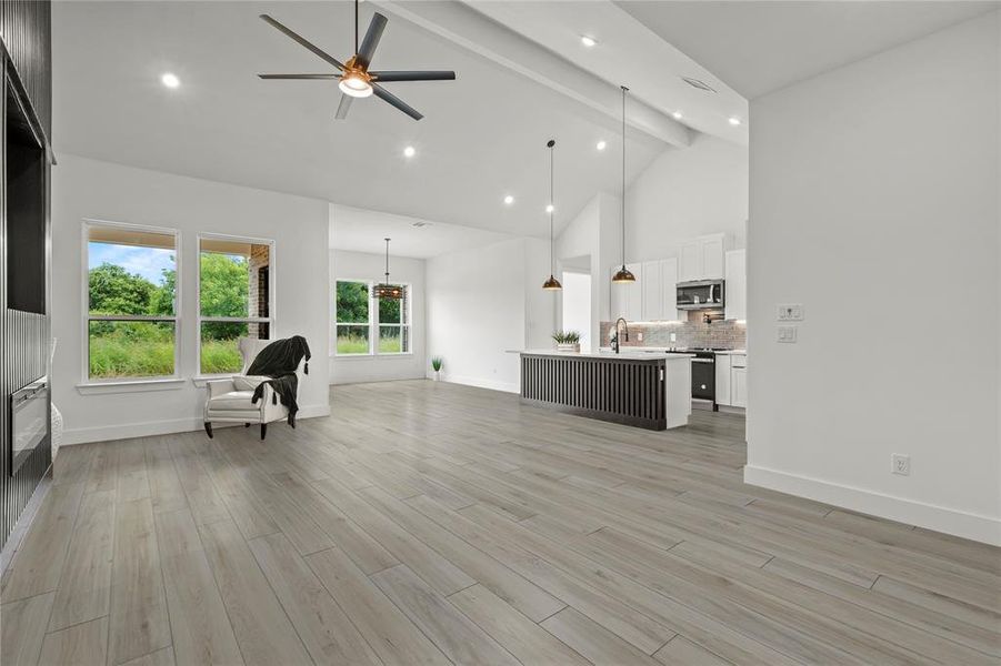 Living room featuring high vaulted ceiling, ceiling fan, beamed ceiling, recessed lighting, and light wood-type flooring