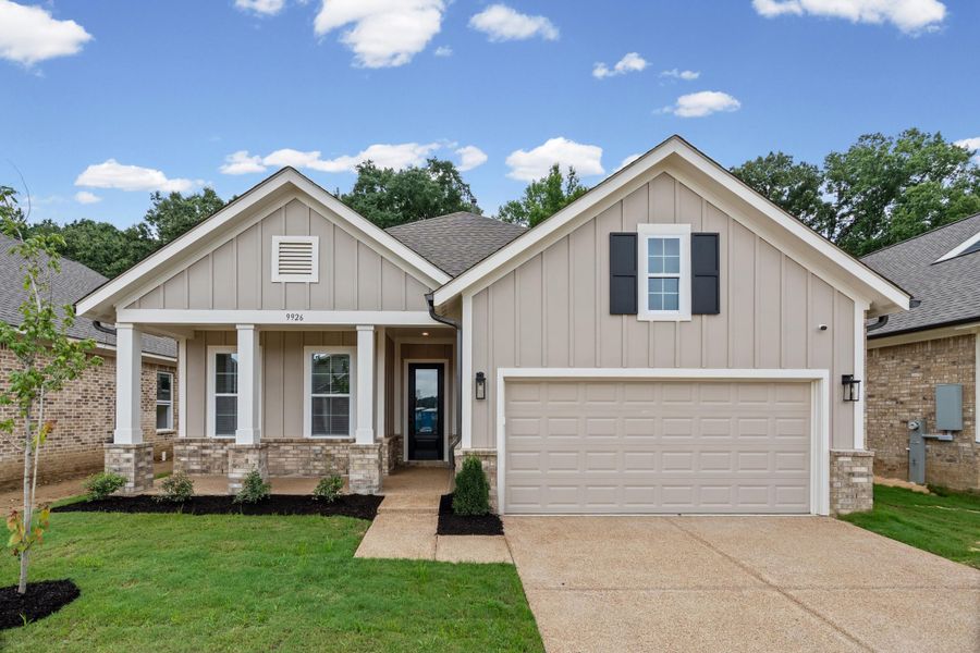 Single-story residence featuring light gray vertical siding, a stone facade foundation, and a covered front porch with white columns Single-story residence featuring light gray vertical siding, a stone facade foundation, and a covered front porch with white columns