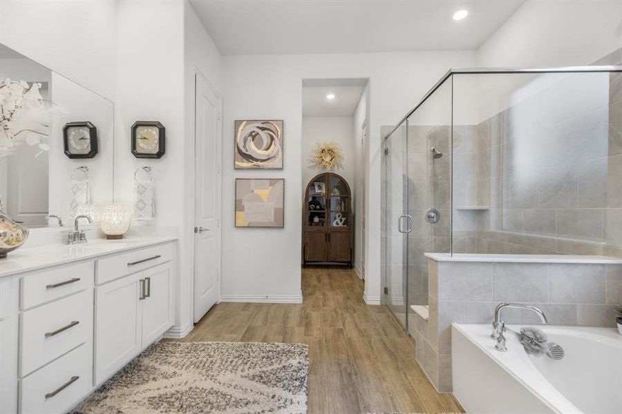 Full bath featuring light wood-style floors, vanity, a bath, and a shower stall Full bath featuring light wood-style floors, vanity, a bath, and a shower stall