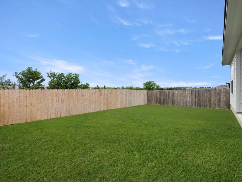A spacious, verdant yard enclosed by wood fencing provides a private outdoor retreat.