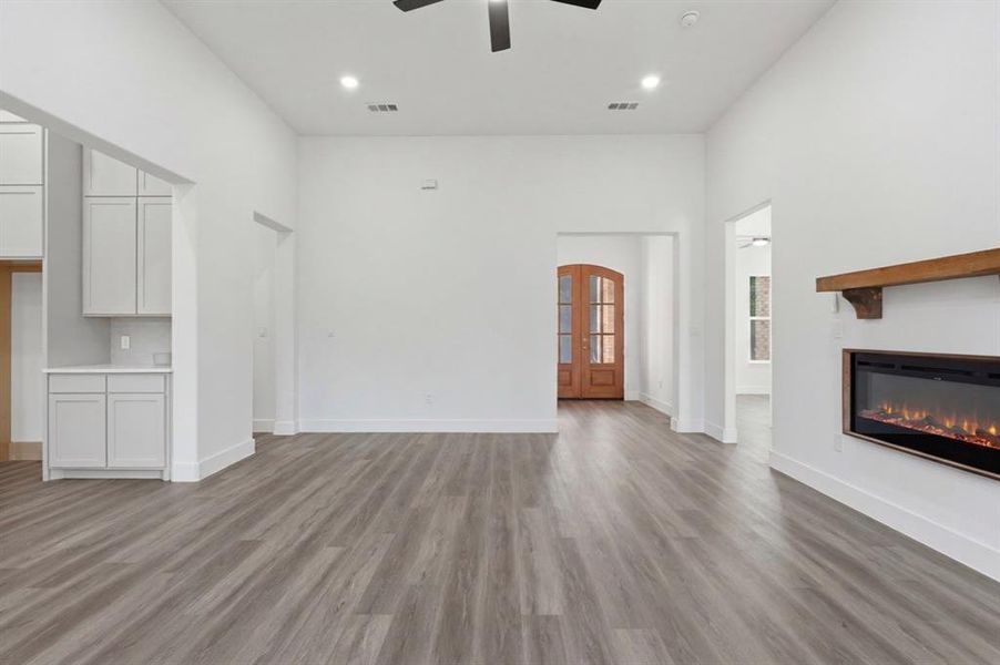 Spacious interior featuring wood-finish flooring and a contemporary fireplace with a rustic wood mantel