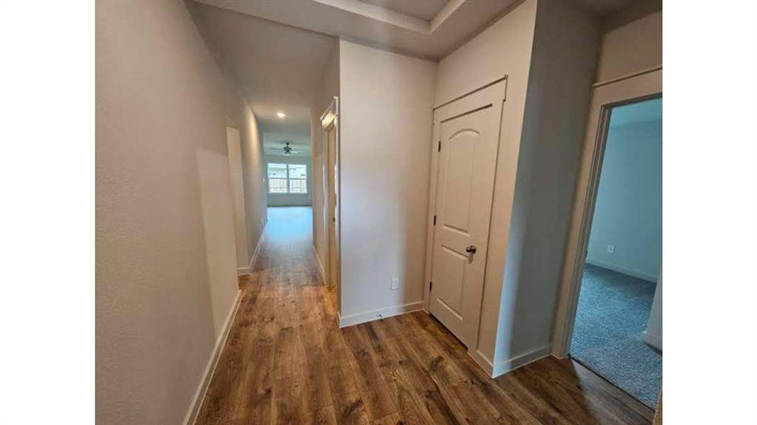 Hallway featuring wood-finish flooring, recessed lighting, and a tray ceiling detail