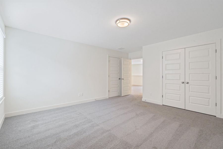 Unfurnished bedroom featuring light carpet and a closet