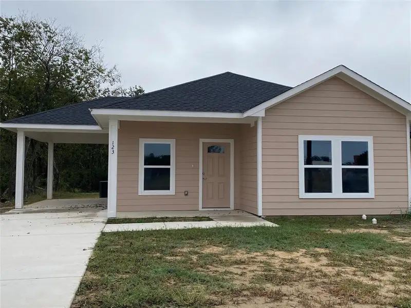 View of front of home with a carport, a shingled roof, driveway, a front lawn, and covered porch View of front of home with a carport, a shingled roof, driveway, a front lawn, and covered porch