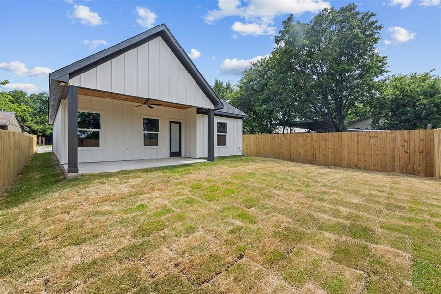 Rear exterior featuring a covered patio with a ceiling fan, a board-and-batten facade, and a private wooden fence