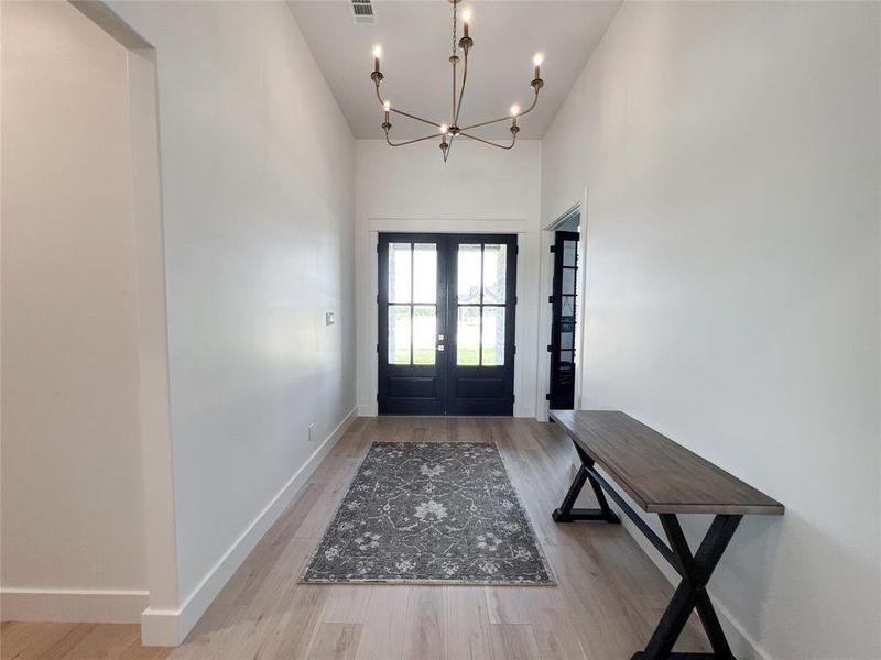 Entryway with light wood finished floors, a chandelier, and french doors