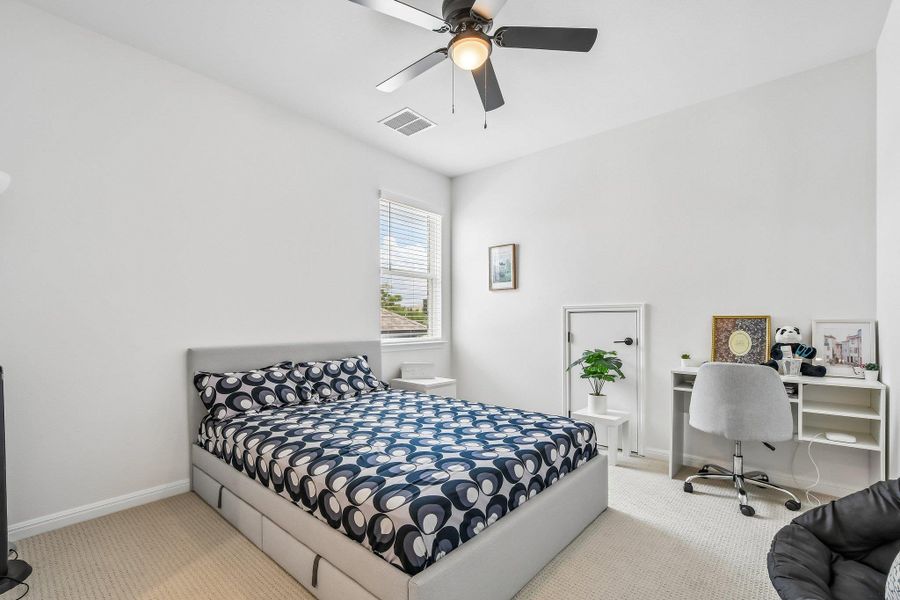A well-lit room featuring a comfortable bed and dedicated workspace with natural light.
