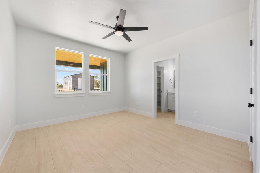 Unfurnished bedroom with a walk in closet, light wood-style floors, and a ceiling fan