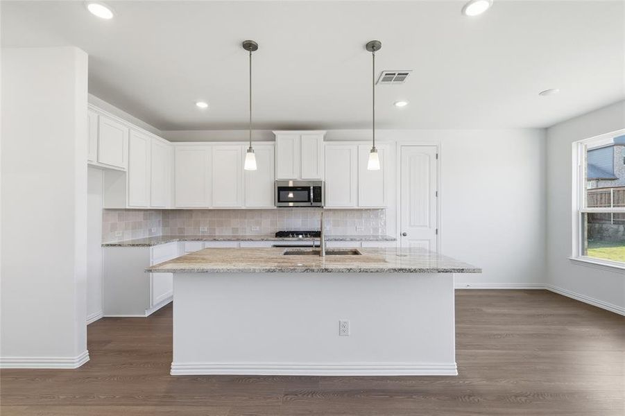 Kitchen with white cabinetry, light stone countertops, tasteful backsplash, pendant lighting, and recessed lighting