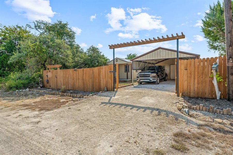 View of yard with dirt driveway and a carport