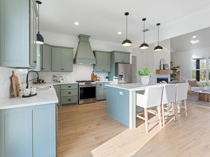 Kitchen with stainless steel appliances, light wood-style flooring, decorative backsplash, decorative light fixtures, and a kitchen bar
