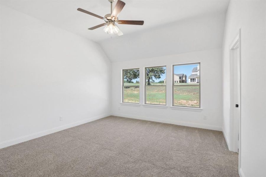 Spare room featuring lofted ceiling, ceiling fan, and light colored carpet