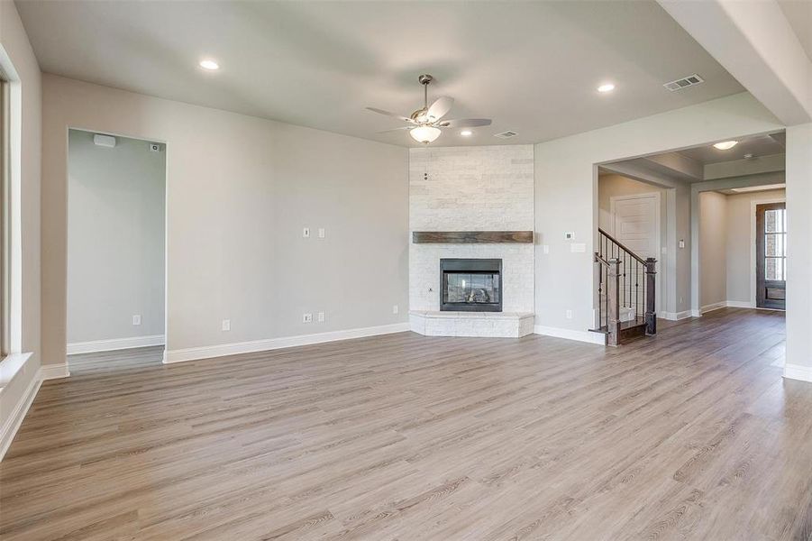 Unfurnished living room featuring a fireplace, light hardwood / wood-style floors, and ceiling fan