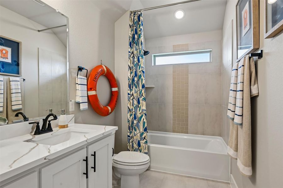 Bathroom with white vanity, tub-shower combo with tile surround, and decorative life preserver on wall Bathroom with white vanity, tub-shower combo with tile surround, and decorative life preserver on wall