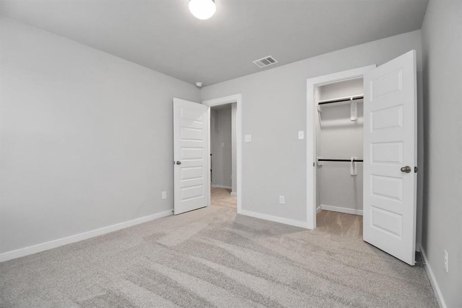 Secondary bedroom features plush carpeting, large windows that let in plenty of natural light, bright paint, and spacious closets. Sample photo of completed home with similar floor plan. Actual colors and selections may vary.