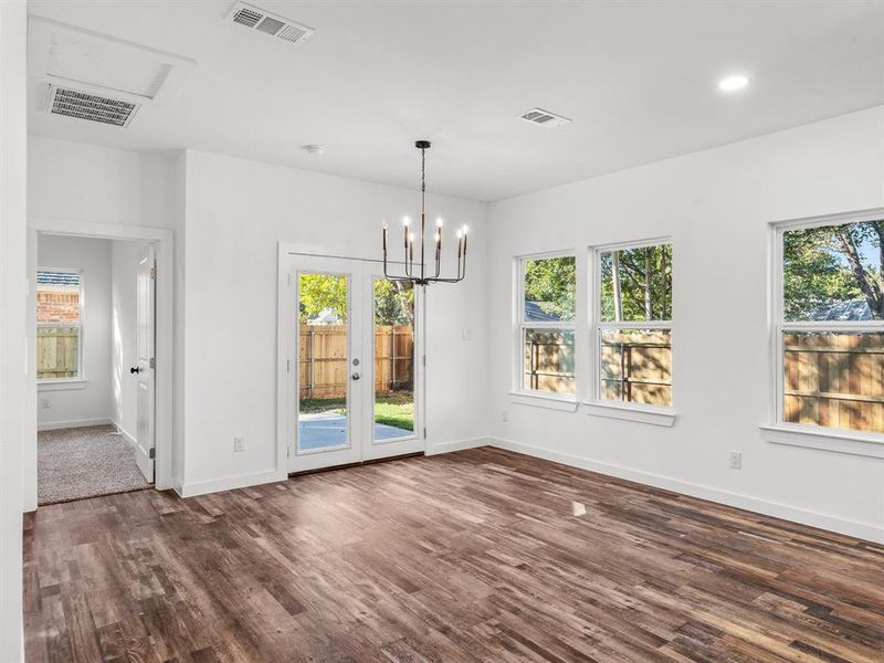 Unfurnished dining area featuring a chandelier, dark wood-style floors, recessed lighting, and french doors