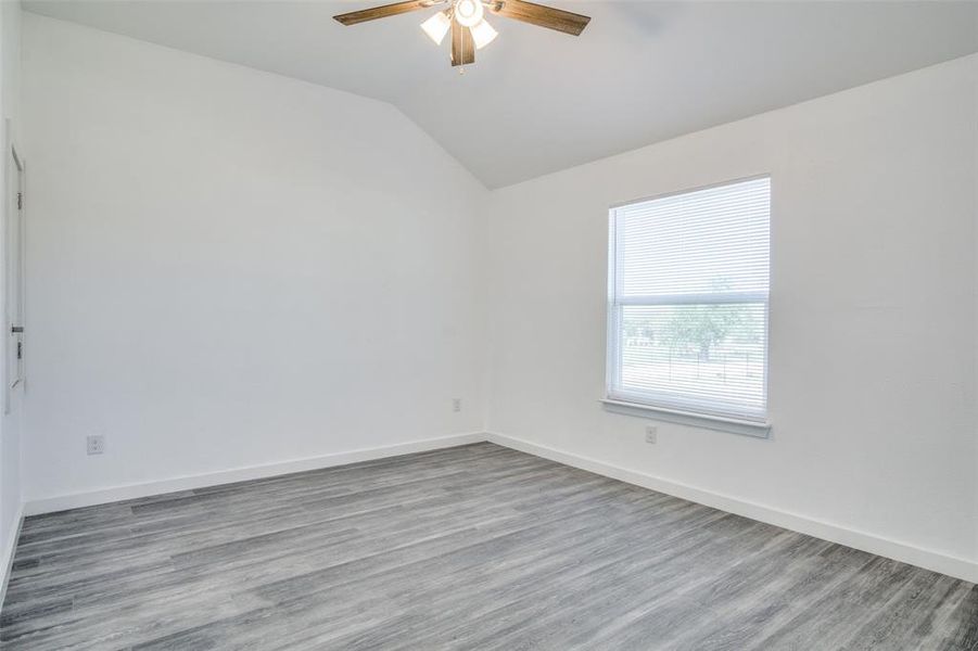 Unfurnished room with vaulted ceiling, ceiling fan, and hardwood / wood-style flooring Unfurnished room with vaulted ceiling, ceiling fan, and hardwood / wood-style flooring