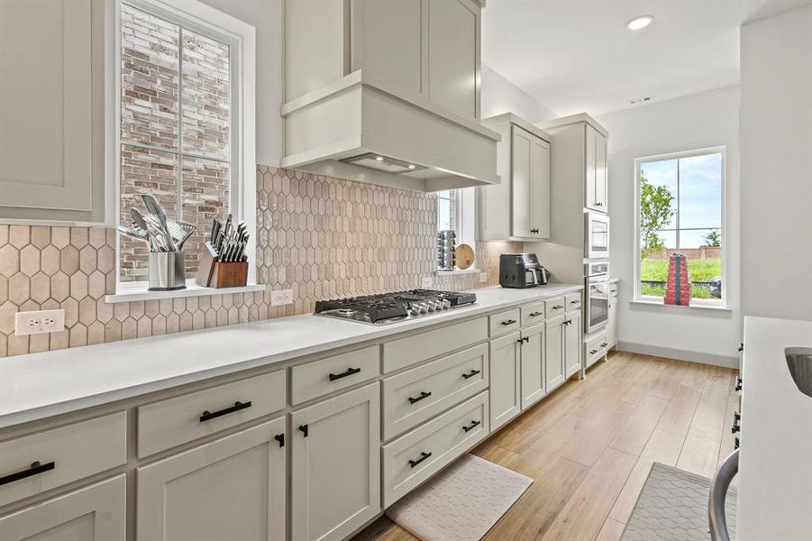 Kitchen featuring tasteful backsplash, light countertops, light wood finished floors, stainless steel appliances, and recessed lighting