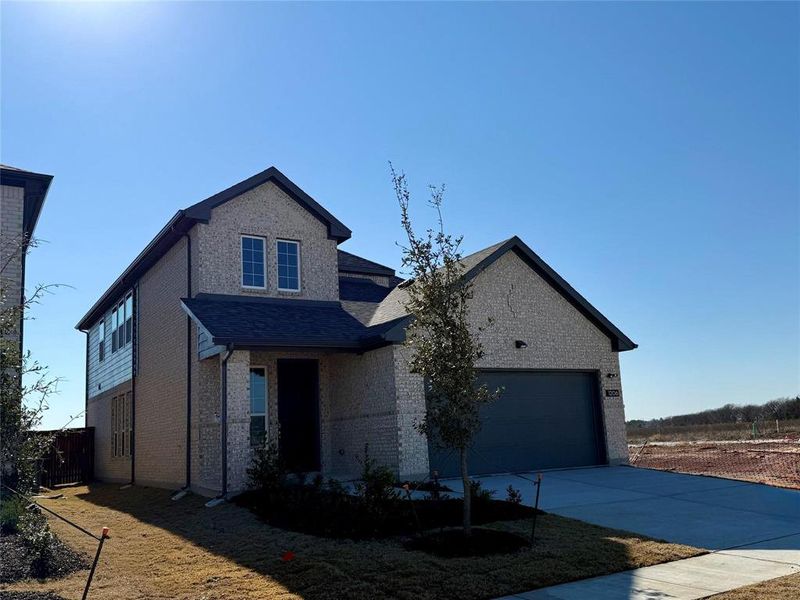 View of front facade featuring a garage, brick siding, and driveway