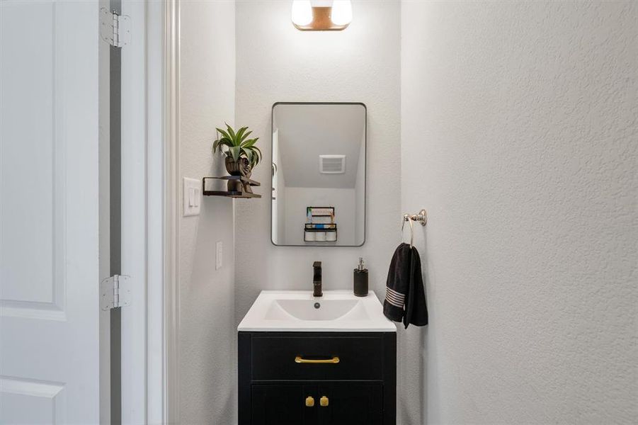 Vanity with a black cabinet, gold-tone hardware, and a white integrated sink