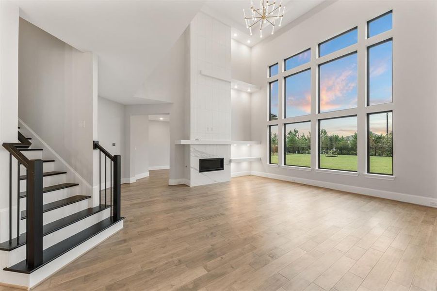 -- Representational Photo -- Another view of this impressive two-story Family Room with floor to ceiling stacked windows, fireplace, and additional staircase leading to the second floor.