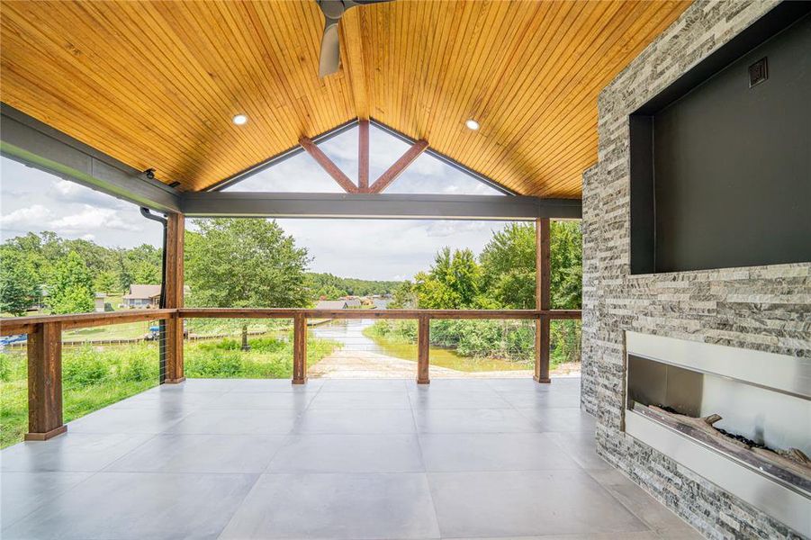 Spacious outdoor covered patio featuring a vaulted wood-finish ceiling with recessed lighting and a ceiling fan