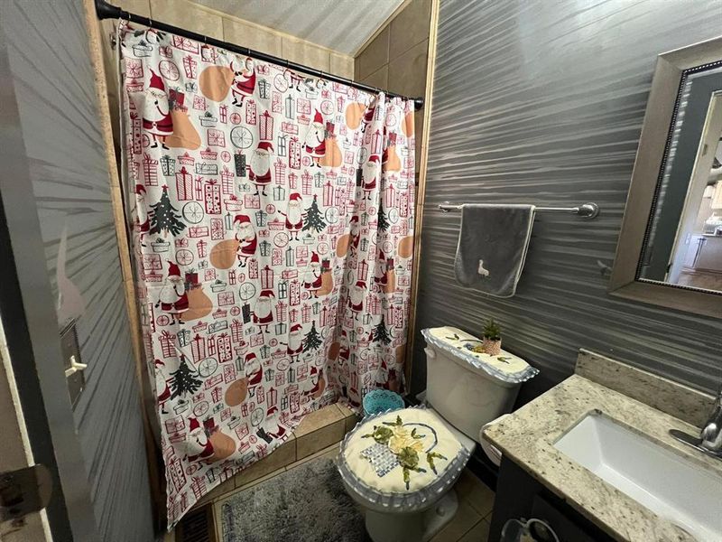 Bathroom featuring tile patterned floors, a shower with curtain, toilet, and vanity