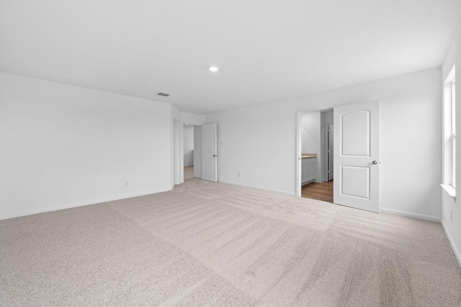 Unfurnished bedroom with light colored carpet, connected bathroom, and recessed lighting