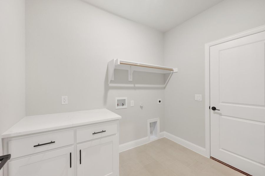 Laundry room with white cabinets, wall-mounted shelf, washer and dryer hookups, and tile floor Laundry room with white cabinets, wall-mounted shelf, washer and dryer hookups, and tile floor