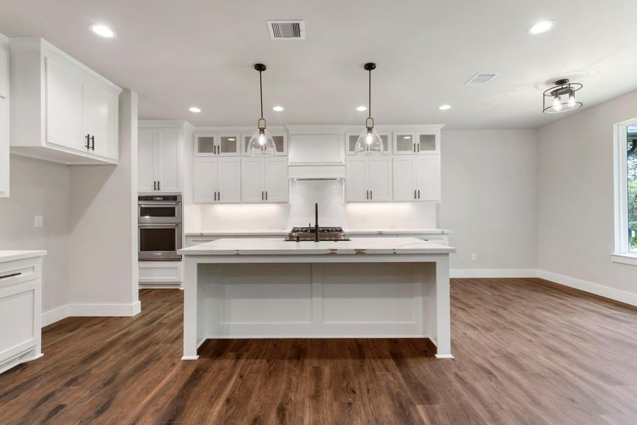 Another view to show off the gas stove and ample natural light from expansive windows, complemented by warm flooring.