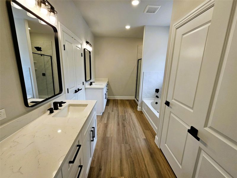 Full bathroom with two vanities, a garden tub, a stall shower, dark wood-style floors, and recessed lighting