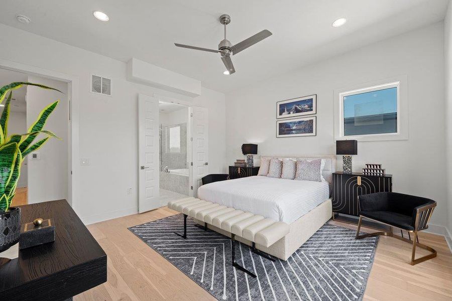 Primary bedroom located on the third floor with wide-plank wood flooring, recessed lighting, and an ensuite bath.