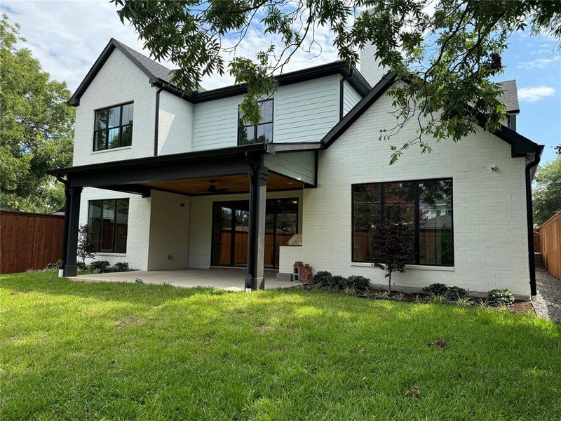 Rear view of house with a patio, ceiling fan, and a lawn