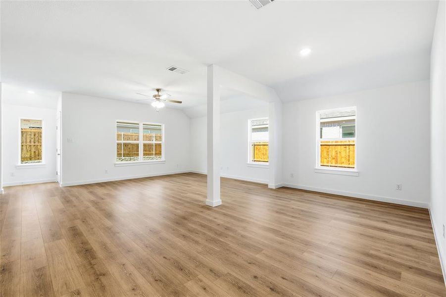 Unfurnished room with lofted ceiling, recessed lighting, light wood-type flooring, plenty of natural light, and a ceiling fan