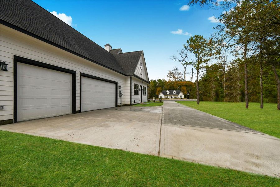 A perspective shot highlighting the privacy and scale of the property. The long driveway and side-loading garage maintain the home's clean curb appeal while offering a grand sense of arrival.