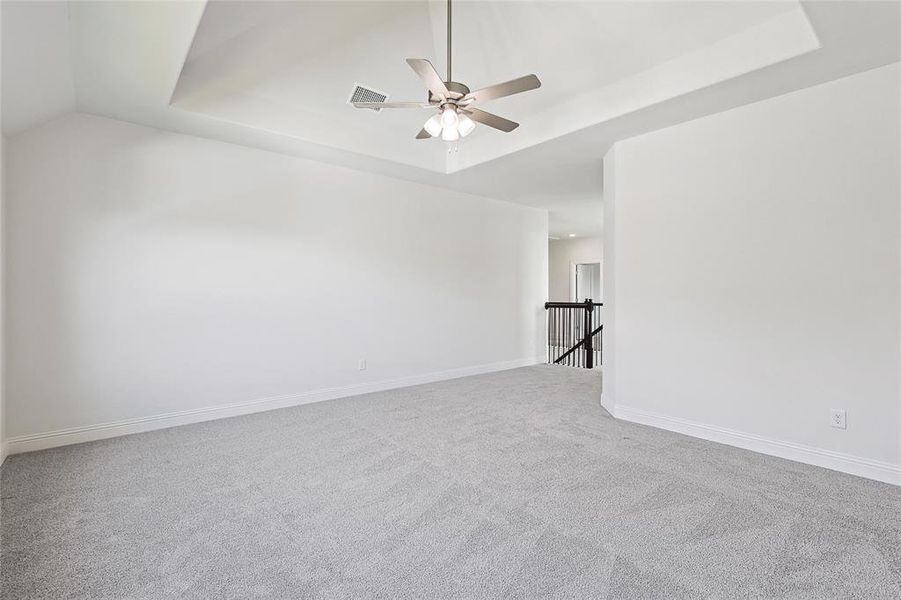 Spare room with ceiling fan, vaulted ceiling, carpet, and a tray ceiling